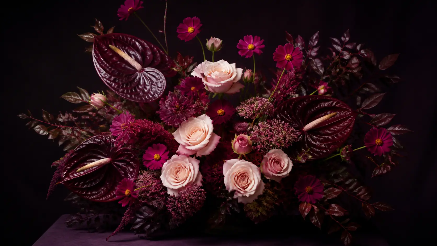 Composition de roses pâles, cosmos framboise et anthuriums prune en atelier