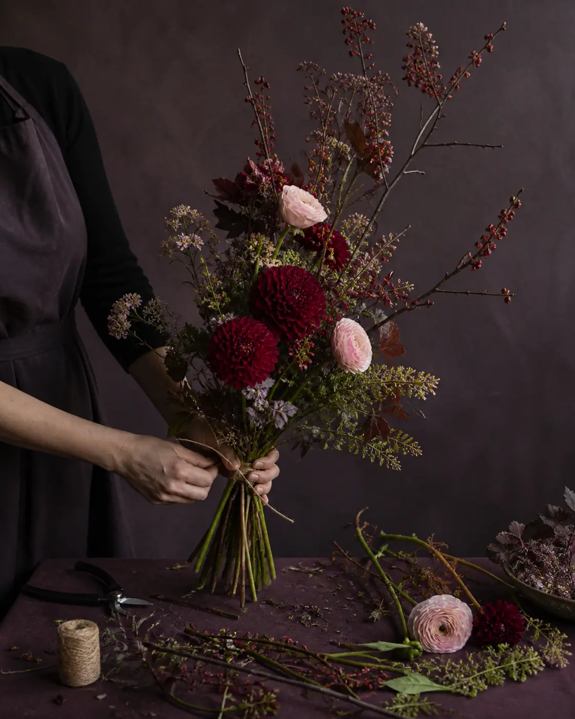Fleuriste assemblant un bouquet vertical de dahlias et de renoncules